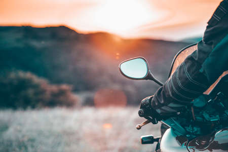 Motorbiker holding steering bar, riding in beautiful sunset. Travel and freedom, outdoor activities concept.の写真素材
