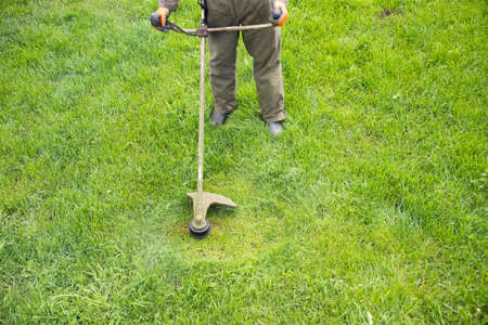 Mowing the grass with a lawn mower. Garden work concept background.