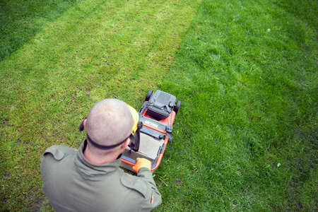 Mowing the grass with a lawn mower. Garden work concept background.