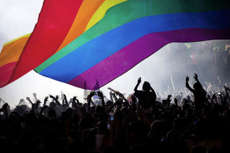 Pride community at a parade with hands raised and the LGBT flag - symbol of love and toleranceの写真素材