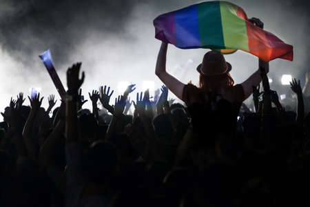 Pride community at a parade with hands raised and the LGBT flag - symbol of love and tolerance