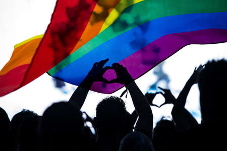 Pride community at a parade with hands raised and the LGBT flag - symbol of love and tolerance