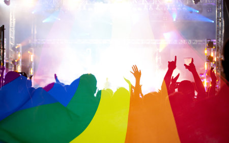 Pride community at a parade with hands raised and the LGBT flag - symbol of love and toleranceの写真素材
