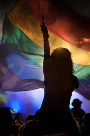 Pride community at a parade with hands raised and the LGBT flag - symbol of love and toleranceの写真素材