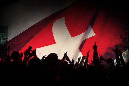 Soccer fans supporting Switzerland - crowd celebrating in stadium with raised hands against...