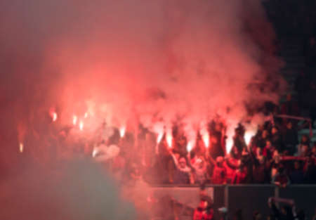 Soccer fans supporting - crowd celebrating in stadium with raised hands against flag