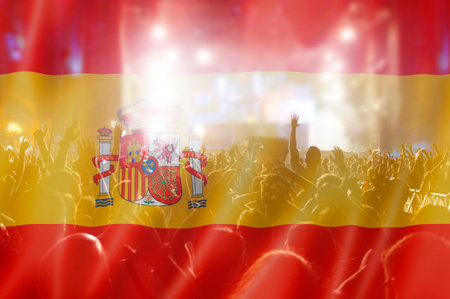 Soccer fans supporting Spain - crowd celebrating in stadium with raised hands against Spain flagの写真素材