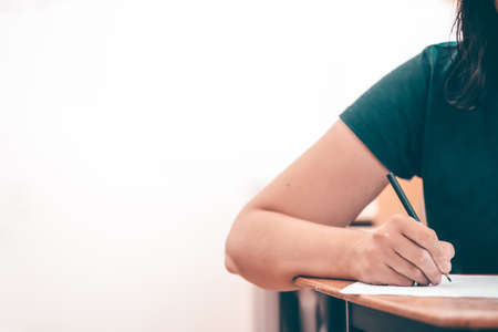 High school or university student holding pencil writing on paper answer sheet. Final exam concept.の写真素材
