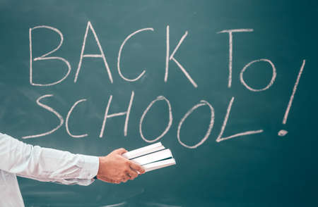 Back to school concept: teacher giving books to her studens in the classroom at the begining of the new school season.の写真素材