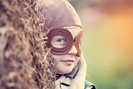 Happy kid playing in pilot helmet pretend to be aviator. Travel, vacation and freedom concept. Childhood, imagination, dream.の写真素材