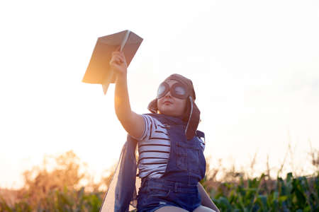 Happy kid playing in pilot helmet pretend to be aviator. Travel, vacation and freedom concept. Childhood, imagination, dream.の写真素材
