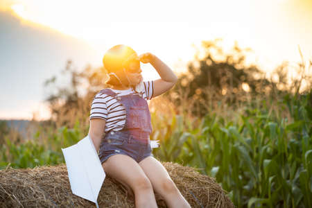 Happy kid playing in pilot helmet pretend to be aviator. Travel, vacation and freedom concept. Childhood, imagination, dream.の写真素材