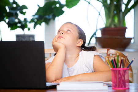 Distance learning-online education. School girl watching online education classes and doing school homework.の写真素材