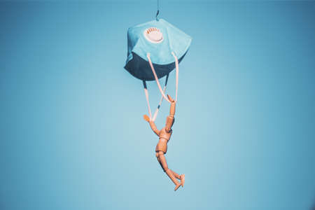 Wooden figure flying with protective mask on blue sky. virus  virus infection concept.の写真素材