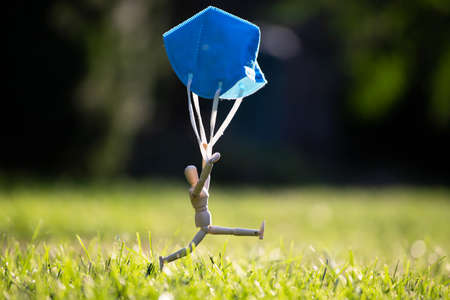 Wooden figure flying with protective mask. virus infection concept.の写真素材