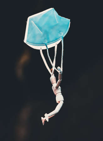 Wooden figure flying with protective mask. virus infection concept.の写真素材