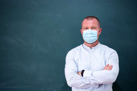 Teacher with face mask welcoming children back at school after lockdown. Back to schoolの写真素材