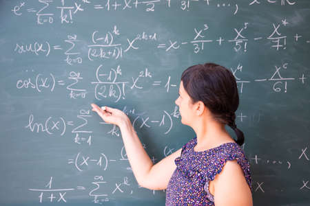 Teacher or student explaning on blackboard during math lesson in school classroom.