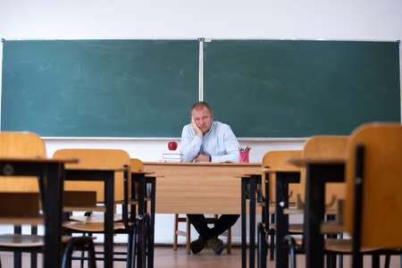Teacher in the classroom in fron of the blackboard. Back to school concept.の写真素材