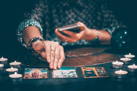 Fortune teller with tarot cards on table near burning candles.Tarot cards spread on table with crystal ball.Forecasting concept.の写真素材