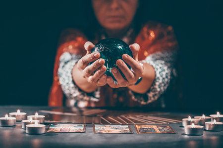 Fortune teller with tarot cards on table near burning candles.Tarot cards spread on table with...