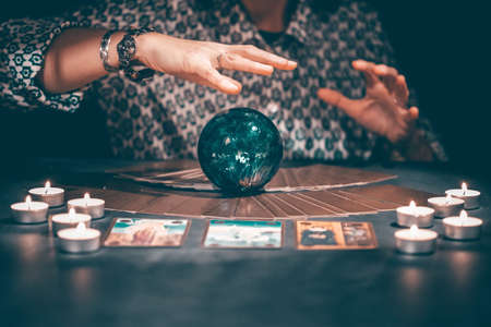 Fortune teller with tarot cards on table near burning candles.Tarot cards spread on table with crystal ball.Forecasting concept.の写真素材