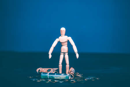 Wooden man standing on a stack of money. Business, financial concept.の写真素材