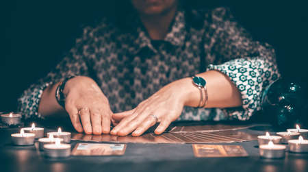 Fortune teller with tarot cards on table near burning candles.Tarot cards spread on table with crystal ball.Forecasting concept.の写真素材