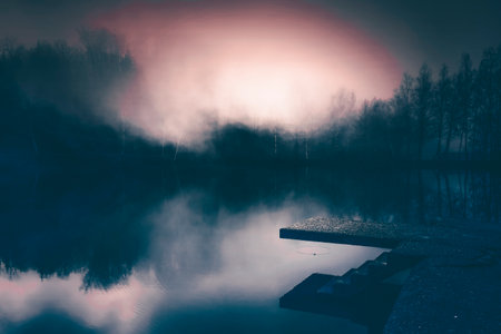 Small lake in enchanted forest in magic, mysterious fog at night. Halloween backgroundの写真素材