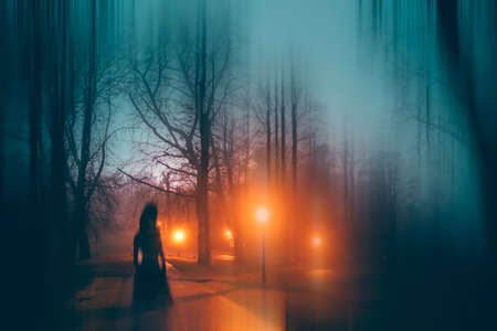 Horror background of a ghostly figure in enchanted a forest on a moody, foggy night. Halloween conceptの写真素材