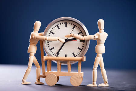 Two wooden figure holding a clock. Time is money, time management, hard working concept.の写真素材