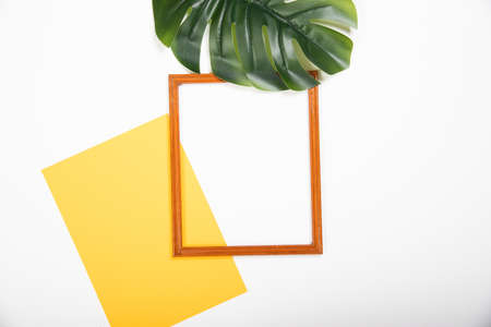 Photo frame with yellow paper blank and tropical palm leaves on white background. Flat lay with copy spaceの写真素材