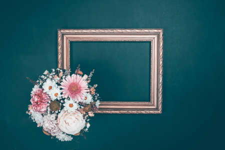 Light pink flowers and empty photo frame for text on vintage blue background. Wall art conceptの写真素材