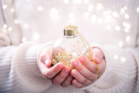 Little girl in winter sweater holds in her hands a Christmas ball.の写真素材