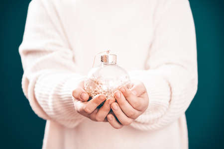 Little girl in winter sweater holds in her hands a Christmas ball.の写真素材