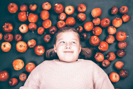 Little girl having fun with red apples. Flat lay photoの写真素材