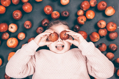 Little girl having fun with red apples. Flat lay photoの写真素材