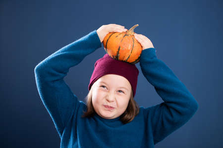 Little toddler girl having fun with pumpkin. Thanksgiving holiday season.の写真素材
