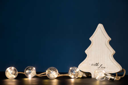 Winter, holidays and decoration concept - wooden christmas tree over sparkling holiday lights