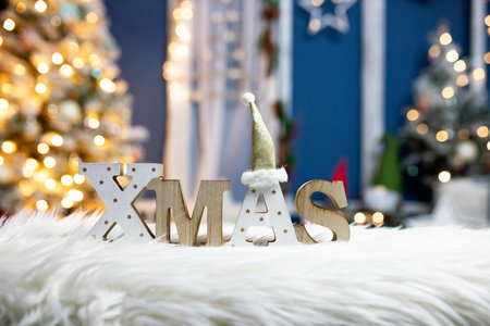 The letters XMAS against sparkling holiday lights and Christmas tree.の写真素材