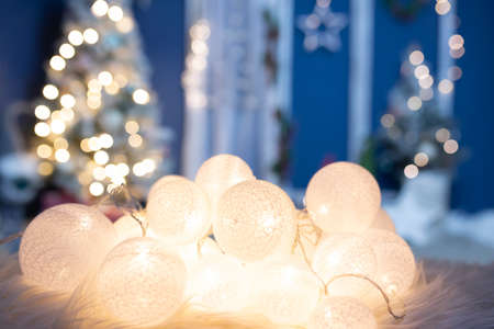 Winter, holidays and decoration concept - close-up on Christmas lights, decorated tree in the backgroundの写真素材