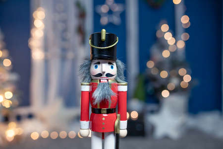 Traditional holiday nutcracker standing in front of decorated Christmas treeの写真素材