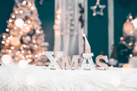 The letters XMAS against sparkling holiday lights and Christmas tree.の写真素材