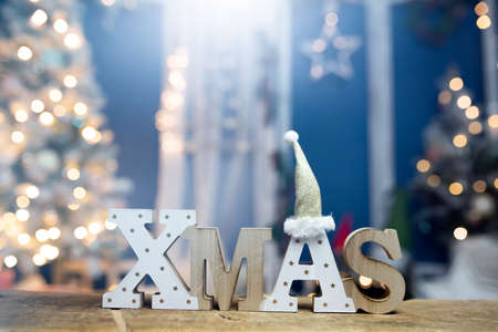 The letters XMAS against sparkling holiday lights and Christmas tree.の写真素材