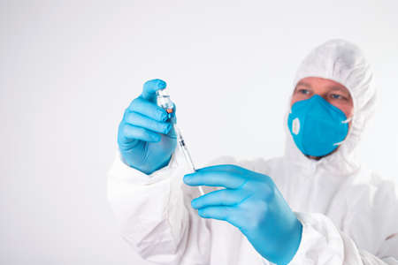 Vaccination concept. Doctor's hand in blue gloves hold medicine vaccine vial bottle and syringe.の写真素材