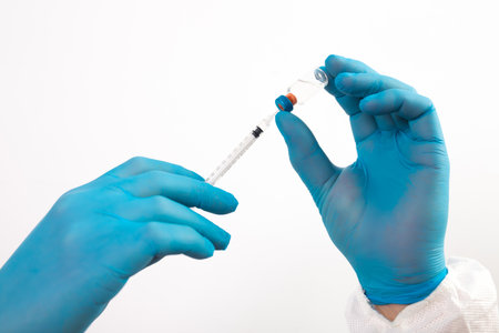 Vaccination concept. Doctor's hand in blue gloves hold medicine vaccine vial bottle and syringe.