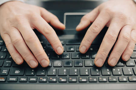 Close up of business man hand working on laptop computer on wooden desk as concept