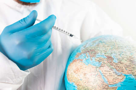 Pandemic concept, close up of scientist injecitng vaccine into the earth. Concept fight against virus.の写真素材