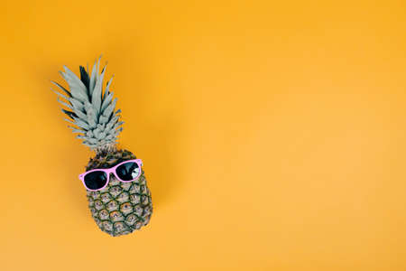 Pineapple with sunglasses on colorful backround. Summer holiday or vacation concept.の写真素材