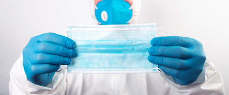 Doctor hand wear blue medical gloves holds antivirus face mask for pandemic diseases.